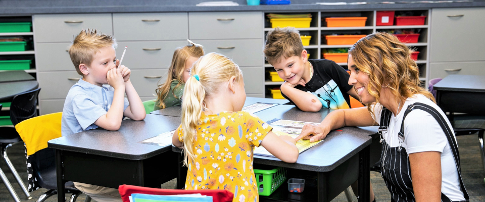 kindergarten classroom with teacher and students around a table kindergarten classroom with teacher and students around a table